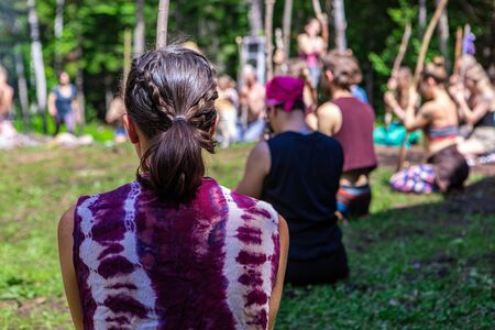 Diverse people enjoy spiritual gathering A group of open minded individuals wearing colorful clothes are seen sitting in a woodland clearing as they practice meditation and contemplation.の写真素材