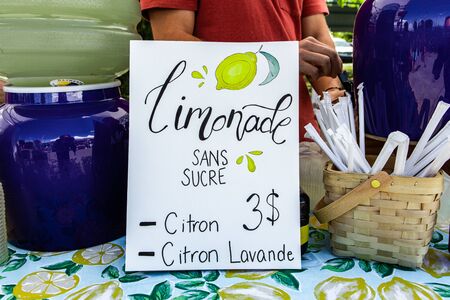 Fresh food at outdoor farmer's market. A colorful French seen is seen closeup, advertising homemade lemonade sold on a market stall during a farmers fair. Sugar free lemon drink mixed with lavender.の写真素材