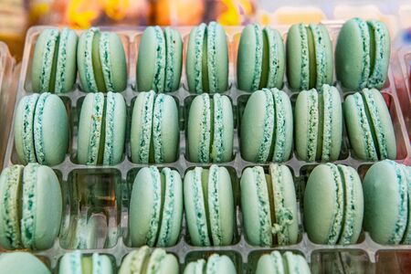 Baked goods at outdoor agriculture fair. A close up view of green colored French macaroons displayed on a market stand during a local farmer's fair. Freshly prepared sweet treats.の写真素材