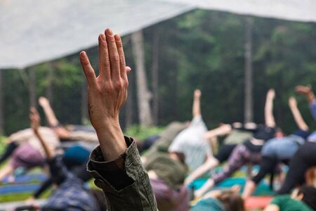 Diverse people enjoy spiritual gathering A close up view on the raised hand of a caucasian person during a set of mindful stretching exercises in nature, with blurry people in background and copy spaceの写真素材