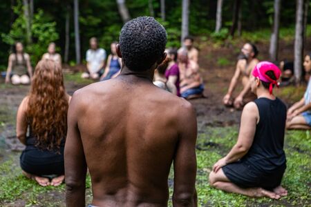 Diverse people enjoy spiritual gathering A multiethnic group of individuals are seen from the rear, kneeling on sacred ground in deep prayer during a retreat celebrating multicultural traditions.の写真素材