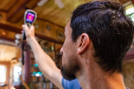 Indoor damp & air quality (IAQ) testing. A domestic environmental inspector is seen carrying out an in depth review of a residential property, using thermal imaging equipment to assess cold bridging.の写真素材