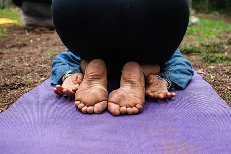 Diverse people enjoy spiritual gathering A close up view on the naked and dirty feet of a person kneeling on a yoga mat in deep meditation during a spiritual retreat to nature.の写真素材