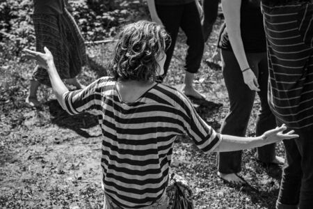 Diverse people enjoy spiritual gathering A high angle and monochrome view of a woman wearing a striped shirt during an outdoor retreat where people seek enlightenment and spiritual guidance.の写真素材