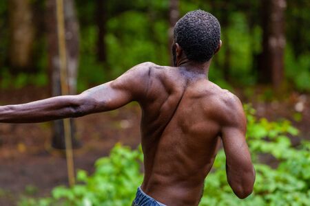 Diverse people enjoy spiritual gathering A healthy African American man is seen shirtless in a forest, practicing mindful yoga poses and stretches during a health and wellbeing retreat.の写真素材