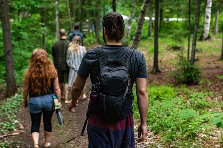 Diverse people enjoy spiritual gathering A muscular bohemian style guy with hair bun is viewed from...