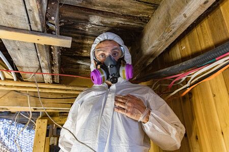 Indoor damp & air quality (IAQ) testing. A close up and front portrait of a man wearing PPE (personal protective equipment) inside a basement during an inspection for black spores & structural defects.の写真素材