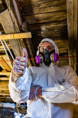 Indoor damp & air quality (IAQ) testing. A low angle and closeup view of a building inspector giving the thumbs up, all is okay, during an indoor environmental (IEQ) assessment, wearing PPE.の写真素材