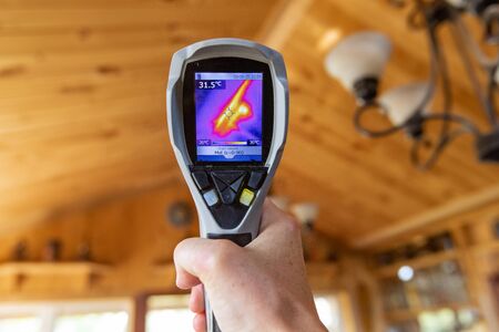 Indoor damp & air quality (IAQ) testing. Cold and hot spots are seen close up on the display of an infrared thermal spot camera during an indoor living environment quality assessment.の写真素材