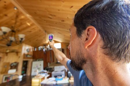 Indoor damp & air quality (IAQ) testing. A close up and rear view of a man using an infrared...