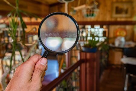 Indoor damp & air quality (IAQ) testing. A closeup view on the hand of a building inspector using a magnification lens to search for signs of damp, rot, mold & mildew inside a residential house.の写真素材