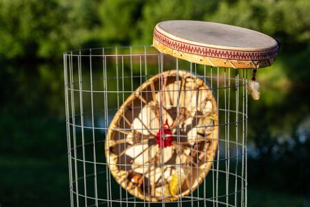 Sacred drums during spiritual singing. Two Native American hand drums are seen closeup, hanging from a mesh waste bin in a park during summer for a cultural music gathering.の写真素材