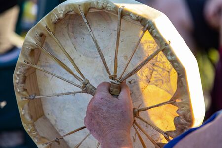 Sacred drums during spiritual singing. A close up view on the hands of an older person holding a...