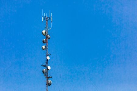 A low angle view of a tall thin cell site lattice tower. Antenna and satellite equipment used in 4G...