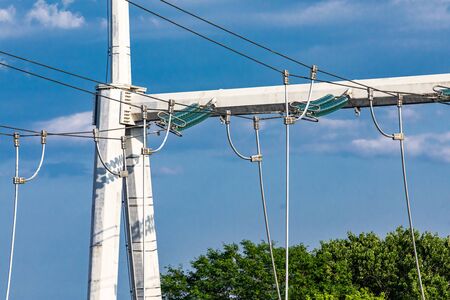 A close up view on a section of an electric pylon with medium volt power lines and insulators,...