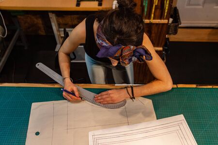 Local eco-designer works on technical fashion drawing. Creative process of a clothes maker. Female designer deep in concentration.の写真素材