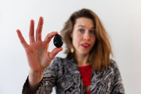 A small kegel egg is viewed close up, in the hand of a surprised looking lady, ancient and sacred...