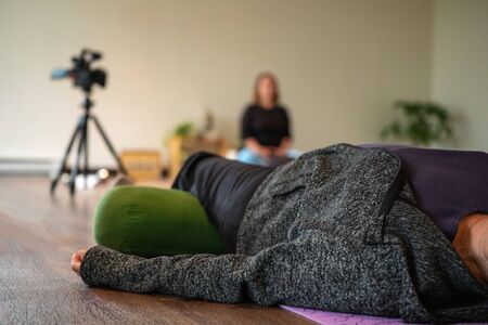 Selective focus photo of group of women attending and practicing yoga and mindfulness inside a classroom of a gym on the floorの写真素材