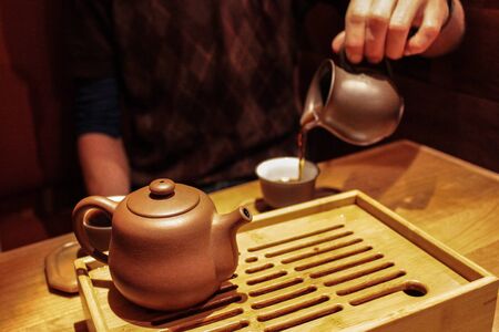 Shot during a gong fu cha tea ceremony with a very small teapot on a tea boat, placed on a wooden tableの写真素材