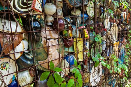 Ourdoor ceramic display with broken pottery items trapped in the walls of an iron framed human-sized maze.の写真素材