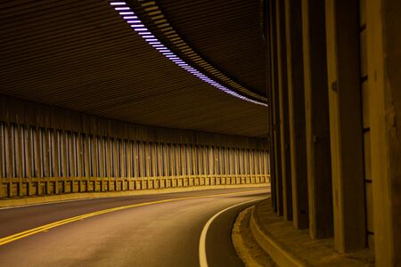 Curve tunnel for automobiles. Empty engineering construction with rhythm of lights and structure. Highway infrastructure.の写真素材