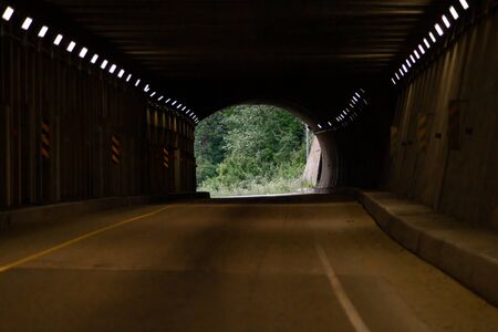 Curve tunnel for automobiles, exit at backgorund. Empty engineering construction with rhythm of...