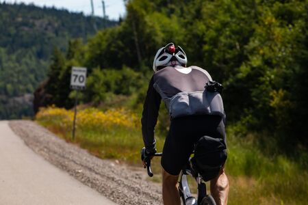 Selective focus on cyclist viewed from the back while cycling a mountain highway with sport clothing...