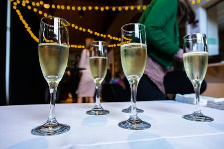 Selective focus of crystal glasses of alcoholic beverages standing on a buffet table with people...