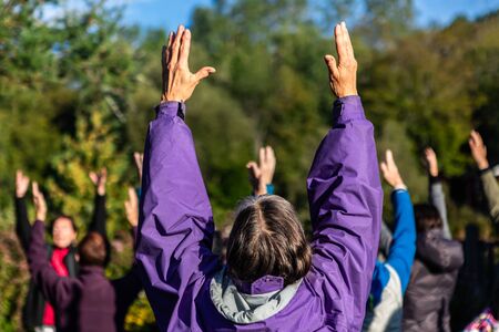 Selective focus and backside view of adult woman participating in yoga lesson with other people in...