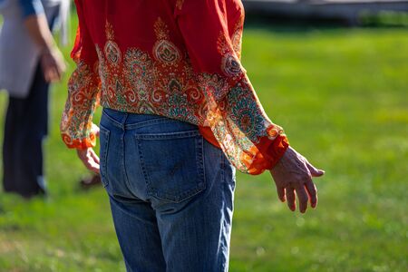Selective focus of adult person spreading her arms while standing outside on grass field in nature...