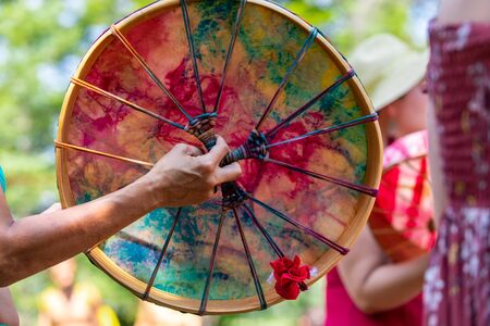 selective focus on caucasian women hand playing Sacred drum, close up on colourful Native American leather drum during a music celebration in a parkの写真素材