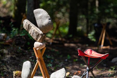 Rock balancing or stone balancing, selective focus of Balanced Stones and Small chair in the forest