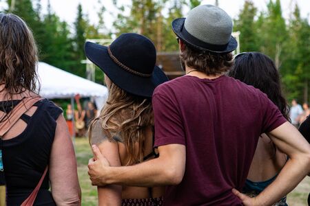 Diverse people enjoy spiritual gathering, A close-up and back view of young man gently hug her girlfriend as they practice shamanic and native traditions in forestの写真素材