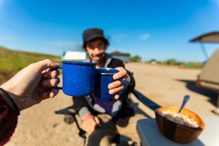 Selective focus of two traveling people clinching their cups of coffee and tea while having some food on the table while beingの写真素材