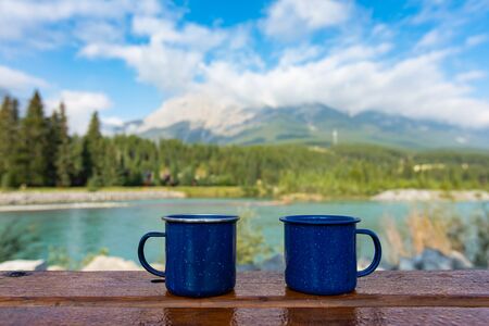 Selective focus of two blue coffee or tea cups standing on a wooden table outdoors with in the...