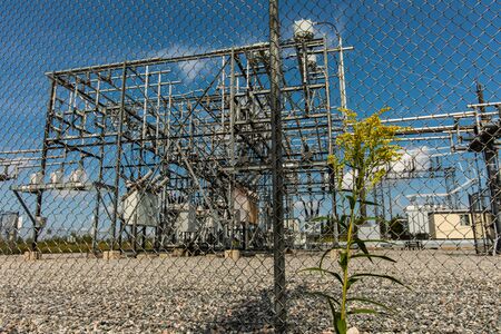 low angle view through the exterior metal fence of an electrical substation, generation,...