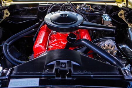 car under hood close up, view of a red engine with big black round air intake filter, tubes, wires,...