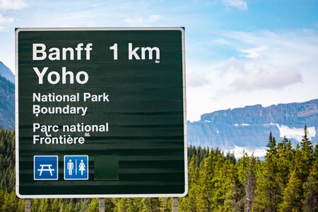Canadian two languages French and English Information road green signs, 1 km to Banff Town, Yoho national park boundary, with symbols, Alberta, Canadaの写真素材