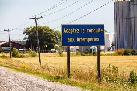French Information Road Sign, Adapt the driving to the weather., on the rural country roadside, with grain silos in the background, Ontario, Canadaの写真素材