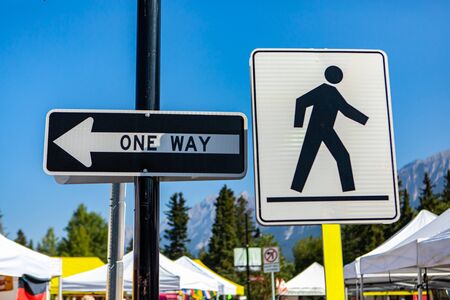 A close up view of a pedestrian zone and one way road signs attached to street poles against a...