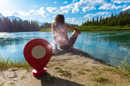 A ens flare from the afternoon sun reflects by a shirtless man enjoying the breathtaking views from a lakeshore in the Rocky Mountains の写真素材