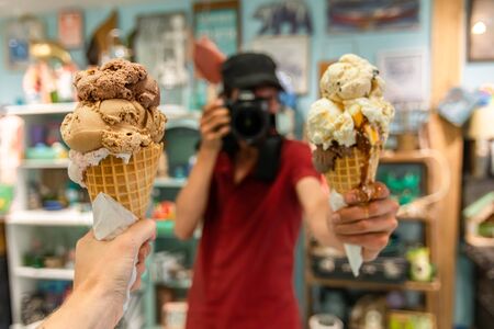 A first person perspective of a woman holding an ice cream cone, in the back ground out of focus a...