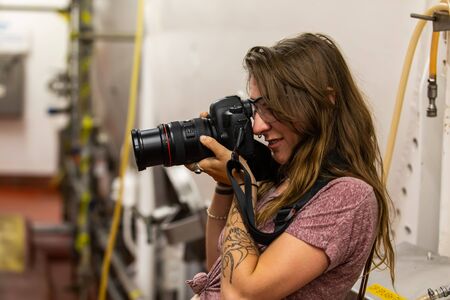 selective focus side view of a young woman with tattoos, wear protection glasses as she takes...