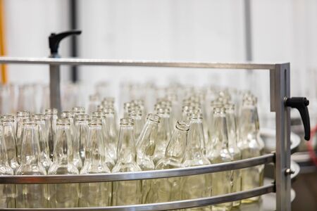 a lot of new white glass empty beer bottles on machine, selective focus close up view, conveyor belt craft brewery factory microbreweryの写真素材