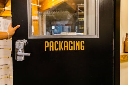 packaging yellow vinyl sticker text Information sign, hand on open black door with a digital lock, industrial room symbolの写真素材