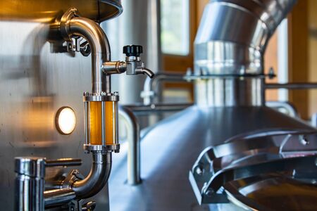 sight glass full of golden beer on stainless steel pipe with hose bib faucet valve and tri clamps...