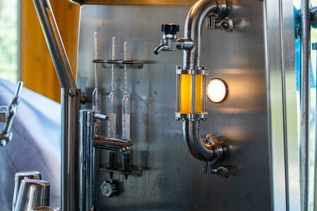 beer quality control equipment, sight glass full of golden beer on stainless steel pipe with light...