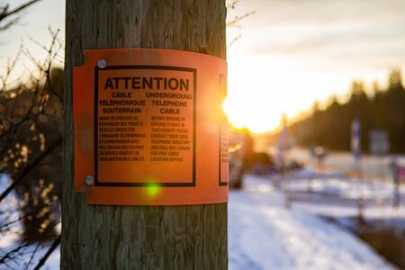 QUEBEC, CANADA - CIRCA DECEMBER 2019 A Bell Canada attention sign is seen on a street pole by a new excavation site, warning of underground cablesのeditorial素材