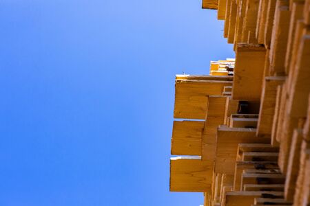 Worms eye perspective of wood boards, treated and stored in a construction yard in tall piles,...