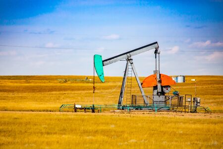 A front view of an aging metal pumpjack and well in Saskatchewan, Canada. Infrastructure of oil and...